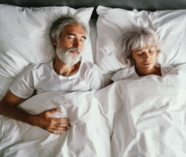 Mann und Frau liegen gemeinsam im Bett und schlafen.