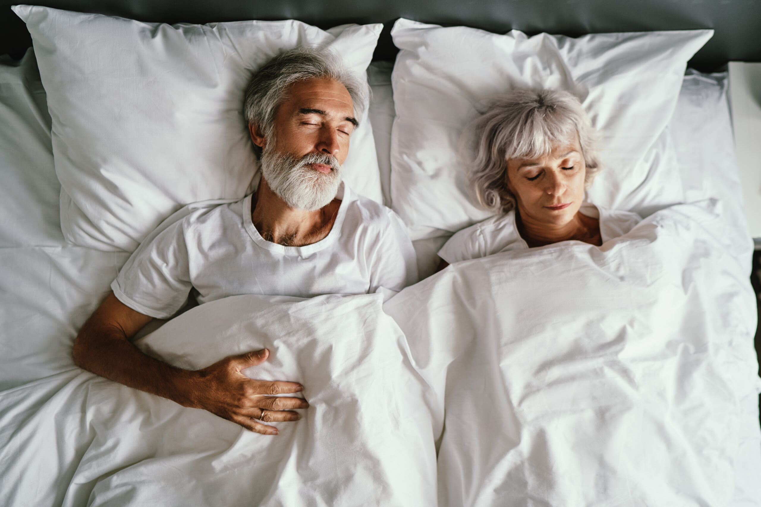 Mann und Frau liegen gemeinsam im Bett und schlafen.
