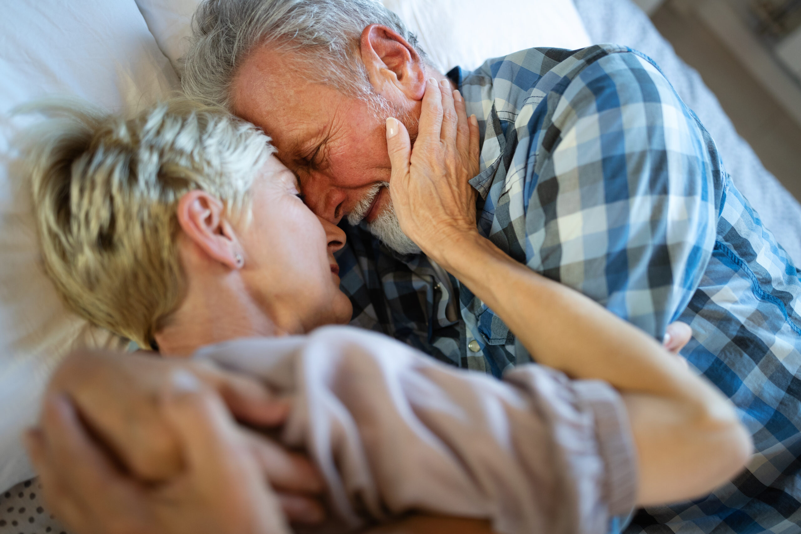 Älteres Paar liegt vertraut im Bett – Verhütung in den Wechseljahren spielt auch in langjährigen Beziehungen eine Rolle.