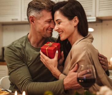 Verliebtes Paar an Valentinstag, die Frau erhält ein Geschenk vom Mann.